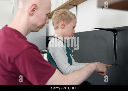 Vater und Sohn machen gemeinsam Hausrenovierungen. Mit Schraubendreher. Vater lehrt Kind Werkzeuge zu verwenden Stockfoto