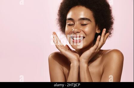 Beauty Face und Spa. Afroamerikanische Frau hat saubere, genährte Haut, spritzt das Gesicht mit Wasser, wäscht sich. Mädchen verwenden Anti-Aging-Kosmetik und Vitamin c Stockfoto