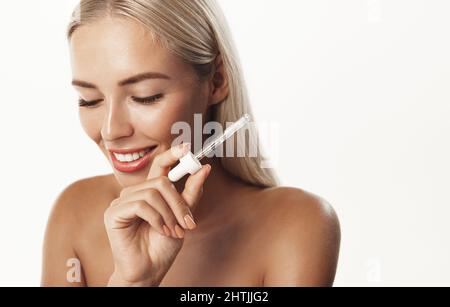 Beauty und Hautpflege Konzept. Lächelnde Frau Anwendung Arganöl essentiell, Balance Hautton mit Vitamin C und Aloe Vera C-Serum Produkt, suchen Stockfoto