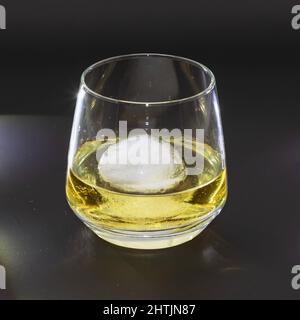 Whiskey auf den Felsen in einem runden Trinkglas als Studioaufnahme mit schwarzem Hintergrund Stockfoto