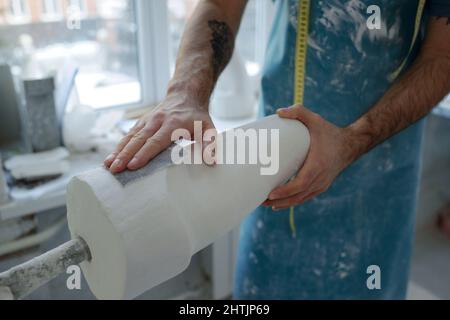 Hände von jungen zeitgenössischen Arbeiter der prothetischen Manufaktur Polieren Gips mit Stück Schleifpapier gegossen Stockfoto