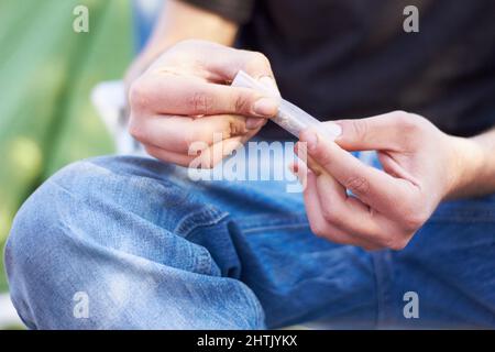 Alles hat ein Tor. Aufnahme einer nicht erkennbaren Person, die ein großes Marihuana-Gelenk rollt. Stockfoto