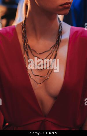 Weibliche Modefigur in rot edel seidiges Kleid und Perlen Hals Accessoire auf der Backstage. Vertikale Modeaufnahme