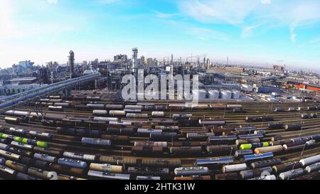 Weitwinkelansicht der industriellen Prozessanlage für Öl- oder Erdölraffinerien mit Tankwagen auf der Schiene, die flüssige und gasförmige Güter transportieren. Stockfoto