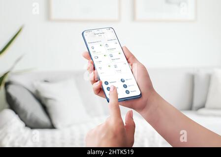 Smart Home Control-App. Automatisierte Steuerung und Überwachung von Home Attributes Konzept. Telefon in Frauenhand Stockfoto