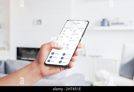 Home Automation App steuert Heimgeräte mit Smartphone-Konzept. Wohnzimmer im Hintergrund Stockfoto