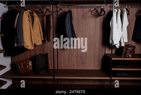 Reihe von Herrenanzügen und Hemd hängen in einem Herrenkleideraum. Ankleideraum in der Wohnung Stockfoto