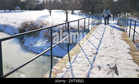 Schwindende Perspektive des Spazierens über die Brücke im Winter. Stockfoto