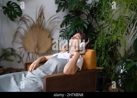 Mädchen Floristin in Kopfhörern Entspannen Sie sich im Garten zu hören Musik nach der Arbeit und Pflege für Pflanzen Stockfoto