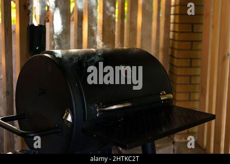 Von einem geschlossenen Grill steigen dicke Rauchschwaden auf. Sommer Erholung im Freien. Weicher, selektiver Fokus. Stockfoto