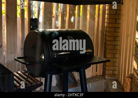 Von einem geschlossenen Grill steigen dicke Rauchschwaden auf. Sommer Erholung im Freien. Weicher, selektiver Fokus. Stockfoto