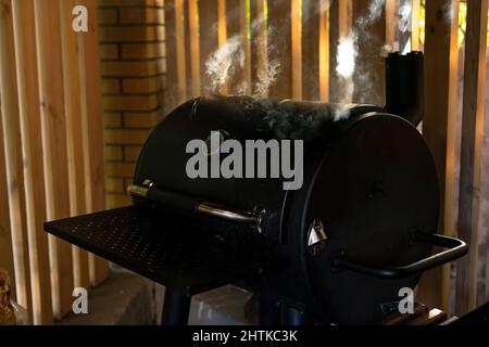 Von einem geschlossenen Grill steigen dicke Rauchschwaden auf. Sommer Erholung im Freien. Weicher, selektiver Fokus. Stockfoto