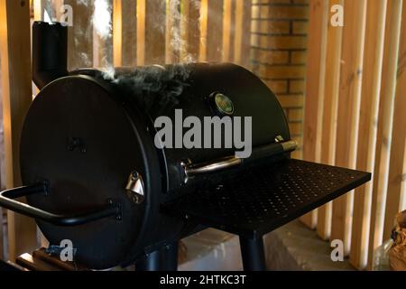 Von einem geschlossenen Grill steigen dicke Rauchschwaden auf. Sommer Erholung im Freien. Weicher, selektiver Fokus. Stockfoto