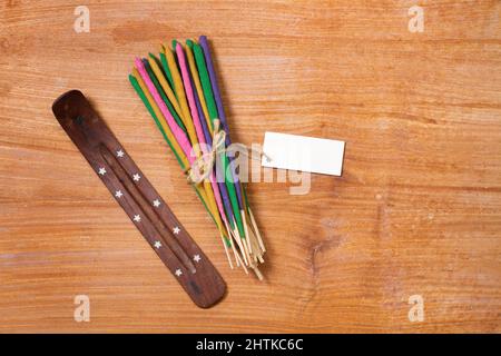 Gefesselte farbige Räucherstäbchen auf einem Holztisch in der Draufsicht Stockfoto