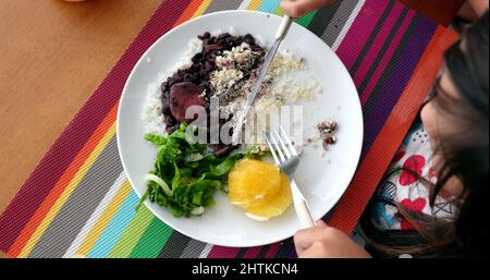 Kinder essen Feijoada traditionelle brasilianische Platte Reis Bohnen und Gemüse Stockfoto