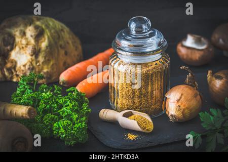 Hausgemachte Gemüsebrühe Pulver, Bio-Gemüsebrühe, mit rohem Gemüse auf schwarzem Hintergrund Stockfoto