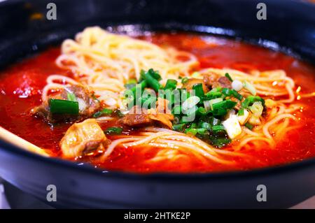 Nahaufnahme der chinesischen Tomatenrindnudelsuppe mit Rindfleisch und gehackten Frühlingszwiebeln darauf. Stockfoto