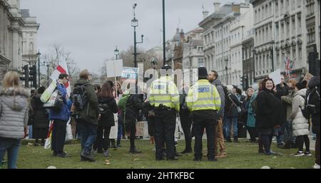 London, Großbritannien - 12 13 2021: Treffen mit Polizeibeamten, die unter einer Schar von Demonstranten Dienst hatten, die bei einer Kundgebung zur Freiheit und gegen Impfungen Schilder hielten. Stockfoto