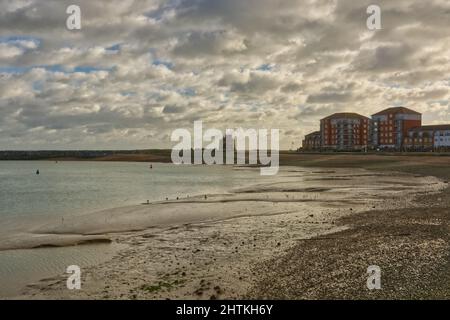 Ebbe am Eingang zum Sovereign Harbour Marina in Eastbourne, East Sussex, England. Mit Martello Tower und Mehrfamilienhäusern, Stockfoto