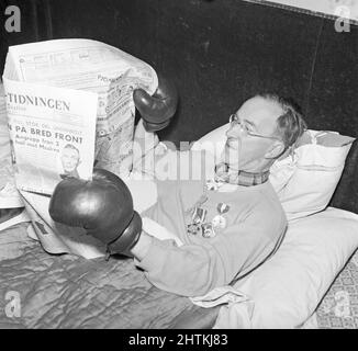 Gökar Well. Richtiger Name Oscar Söderlund Sportjournalist. 1892-1965 im Bett abgebildet und liest das Papier und hält es mit seinen Boxhandschuhen. Schweden 1943 Kristoffersson Ref. C80-3 Stockfoto