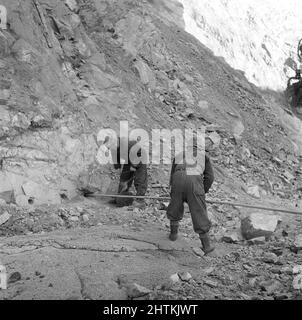 Kiruna Schweden im Jahr 1950s. Die offene Mine und die Arbeiter bohren Löcher, um Sprengstoffe einzubringen. Das Bild zeigt, wann das Loch fertig gebohrt ist und die Sprengstoffe mit einer langen Stange in das Loch gedrückt werden. Schweden 1954 Kristoffersson BP24-1 Stockfoto