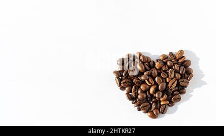 Herzform von Robusta, Arabica-Kaffeebohnen isoliert auf weißem Hintergrund, Banner, Kopierbereich. Kaffeebohnen für Latte, Cappuccino, Mokka, Americano CO Stockfoto