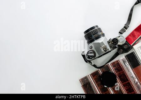 Retro-Filmkamera mit Filmstreifen auf weißem Hintergrund. Flach liegend, Draufsicht Stockfoto