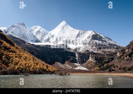 Landschaft des heiligen Berges Yangmaiyong und des Sees auf dem Hochland an sonnigen Tagen im Yading Naturschutzgebiet, Daocheng, China Stockfoto