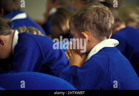 Grundschulkinder Gebete in der Versammlung Stockfoto