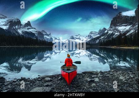 Reisende Frau sitzt im Kanu mit aurora Borealis über Spirit Island im Maligne Lake im Jasper National Park, Alberta, Kanada Stockfoto