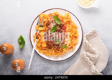 Tagliatelle Pasta mit Fleischbällchen in Tomatensauce und Thymian in Sauce auf hellgrauem Schiefer, Stein oder Beton Hintergrund. Traditionelles italienisches Gericht und Cu Stockfoto