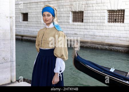 Frau in einem wunderschönen, traditionellen venezianischen Kostüm und Maske, die sich wie Vermeer's Girl mit einem Perlenohrring auf dem Venedig-Karneval in venedig, Italien, ausgibt Stockfoto