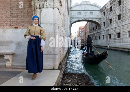 Frau in einem wunderschönen, traditionellen venezianischen Kostüm und Maske, die sich wie Vermeer's Girl mit Perlenohrring in der Nähe von Ponte della Paglia, Venedig-Karneval ausgibt Stockfoto