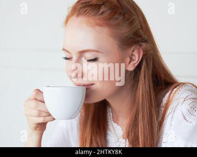 Es gibt nichts Besseres als frischen Kaffee am Morgen. Eine kleine Aufnahme einer jungen Frau, die in einem Café Kaffee trinkt. Stockfoto