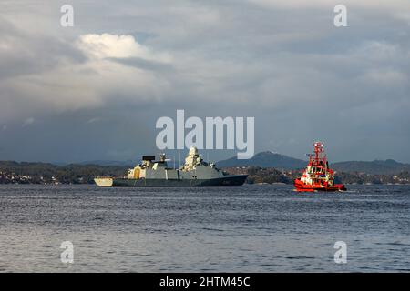 Dänische Fregatte der Ver Huitfeldt-Klasse F362 HDMS Peter Willemoes in Byfjorden, vor dem Hafen von Bergen, Norwegen. Schlepper BB Coaster in der Nähe. Eine dunkle, regnerische A Stockfoto