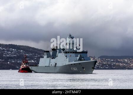 Dänische Fregatte der Ver Huitfeldt-Klasse F362 HDMS Peter Willemoes in Byfjorden, vor dem Hafen von Bergen, Norwegen. Schlepper BB Coaster in der Nähe. Eine dunkle, regnerische A Stockfoto