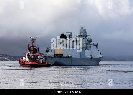 Dänische Fregatte der Ver Huitfeldt-Klasse F362 HDMS Peter Willemoes in Byfjorden, vor dem Hafen von Bergen, Norwegen. Schlepper BB Coaster in der Nähe. Eine dunkle, regnerische A Stockfoto