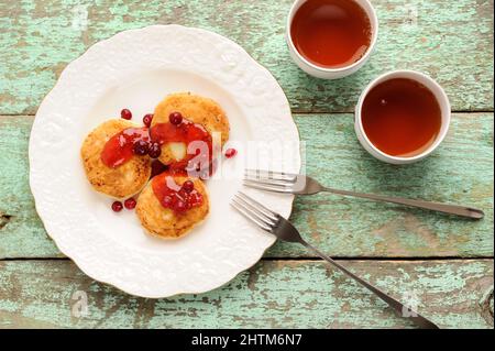 Hausgemachte Syrniki, russische Hüttenkäse-Pfannkuchen mit Himbeermarmelade und Preiselbeeren von oben Stockfoto