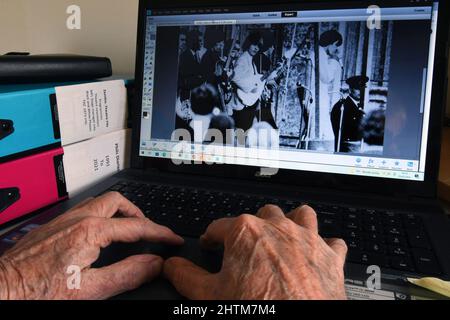 Alte Hände an einer Computertastatur, die Bilder finden, um angenehme Erinnerungen auszulösen, wenn man älter wird. Musik spielte eine wichtige Rolle im Leben in den 1960' Stockfoto