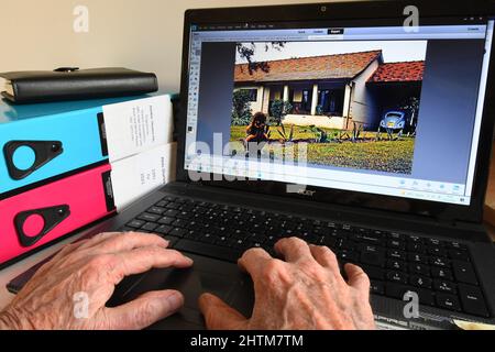 Alte Hände an einer Computertastatur, die Bilder finden, um angenehme Erinnerungen auszulösen, wenn man älter wird.Leben als Expatriate, der in Sambia während der 19 arbeitet Stockfoto