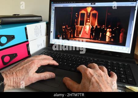 Alte Hände an einer Computertastatur finden Bilder, um angenehme Erinnerungen auszulösen, wie man älter wird.Diese Produktion des Musicals 'My Fair Lady' in der Stockfoto