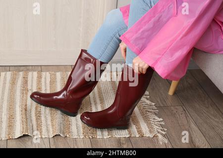 Frau, die im Flur Gummistiefel anlegt Stockfoto