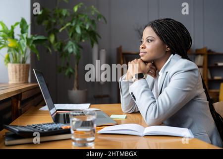 Abgelenkt von einer Geschäftsfrau am Schreibtisch mit Laptop blicken sie im Fenster nachdenklich über das Problem Stockfoto
