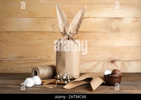 Osterhasen-Geschenktasche, Süßigkeiten und Seil auf Holzhintergrund Stockfoto