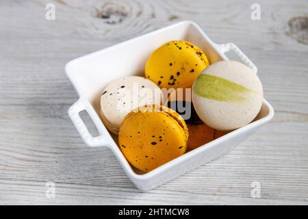 Gelbe und weiße Makronen in einer weißen Porzellanschale Stockfoto