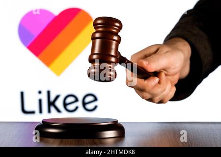 Gavel in Richterhand vor dem Hintergrund der kurzen Likee Video-Sharing-Service-Logo. Das Konzept des Trials. Stockfoto