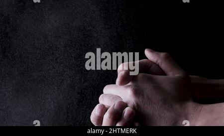 Baumwollhände mit Mehl auf schwarzem Hintergrund. Rahmen. Der Koch klatschte mit Mehl überzogene Hände. Stockfoto