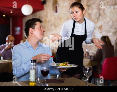 Wütender Mann, der sich bei der sich entschuldigenden Kellnerin über das Essen im Restaurant beschwerte Stockfoto