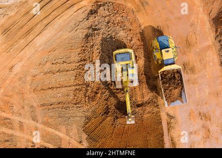 Luftaufnahme auf Baggern Arbeiten auf der Baustelle Dumping Erde für die Verladung auf Muldenkipper Stockfoto