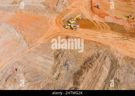 Luftaufnahme am Bagger lädt die Erde in einen großen Muldenkipper Stockfoto
